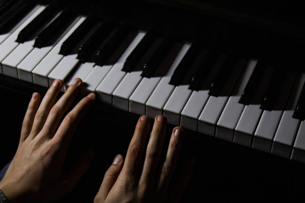 two male hands on the piano. palms lie on the keys and play the keyboard instrument in the music school. student learns to play. hands pianist. black dark background. - Valokuva, kuva