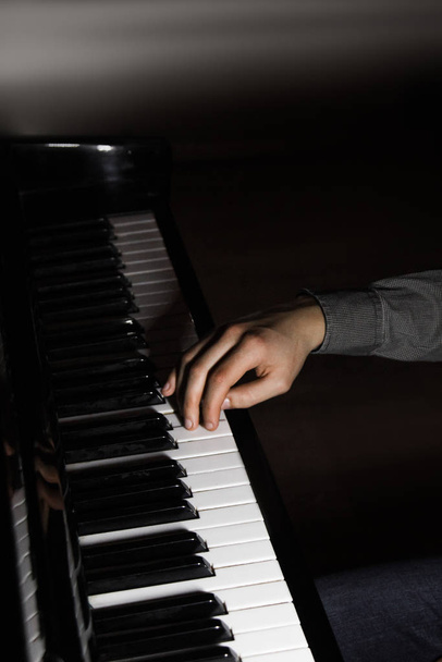 one male hand on the piano. The palm lies on the keys and plays the keyboard instrument in the music school. student learns to play. hands pianist. black dark background. - Valokuva, kuva