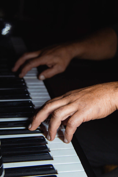 two male hands on the piano. palms lie on the keys and play the keyboard instrument in the music school. student learns to play. hands pianist. black dark background. - Photo, image