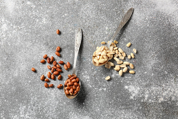 Spoons with peanuts on grey background - 写真・画像
