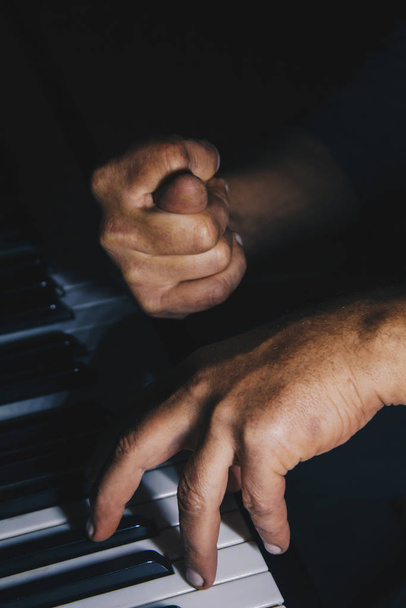 two male hands on the piano. palms lie on the keys and play the keyboard instrument in the music school. student learns to play. hands pianist. black dark background. - Foto, afbeelding