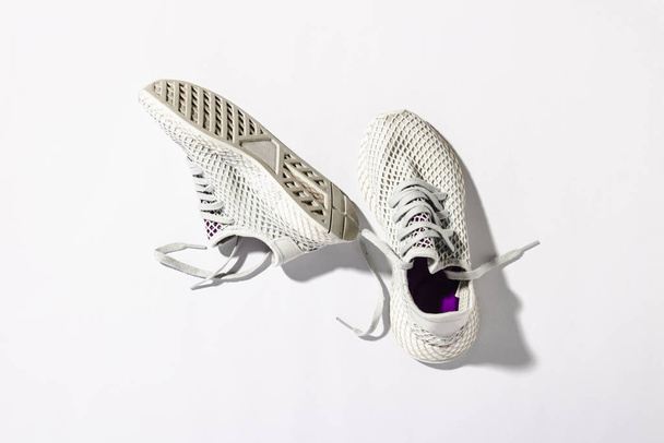 Sneakers on a white background under the morning sun. The concept of running, fitness, cross fit. Morning running. Natural light. Flat lay, top view - Photo, Image