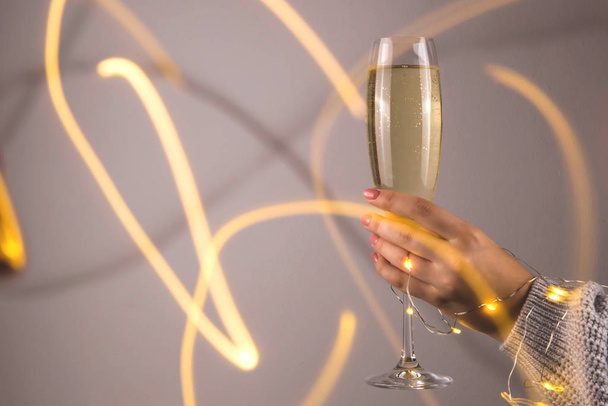 Minimalistisches Weihnachtskonzept aus Champagner in weiblicher Hand. - Foto, Bild