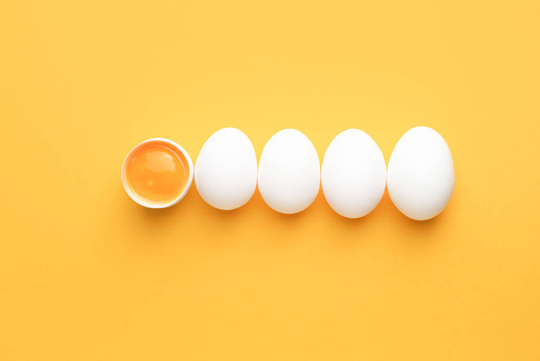 Broken egg among whole ones on color background. Concept of uniqueness - Foto, Imagen