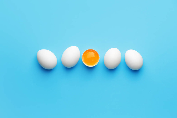Broken egg among whole ones on color background. Concept of uniqueness - 写真・画像