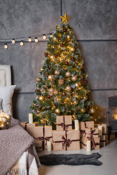 a dark room with a bed and many decorations and lights, a Christmas tree with gifts under it, a gray wall with bulbs - Photo, Image