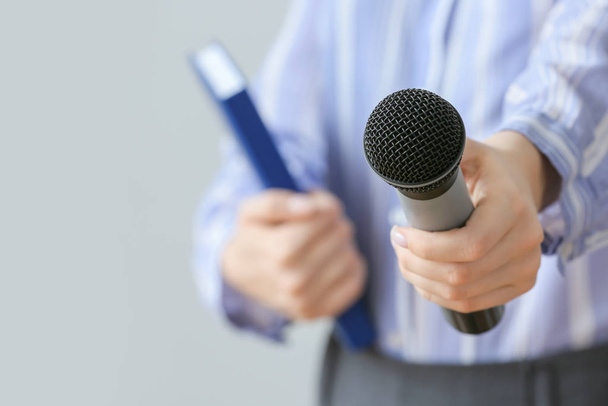 Journalist mit Mikrofon auf grauem Hintergrund, Nahaufnahme - Foto, Bild