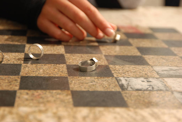 Silver wedding rings and woman's hand on the chess board. Concept of love, marriage, together, game, lovers. - Foto, Imagem