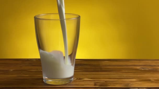 Lanie mleka od dzbanka do szklanki na wiejskim drewnianym stole - Materiał filmowy, wideo