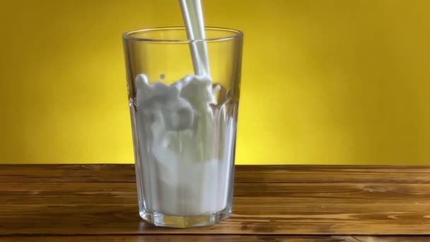 Nalévání mléka z džbánu na sklo na dřevěný stůl - Záběry, video