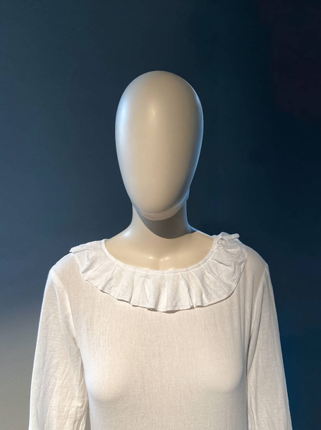 3D маленька фотографія жінки-манекена в білій сукні з коміром з студійним світлом, синьо-білим перед темно-синьою стіною
 - Фото, зображення