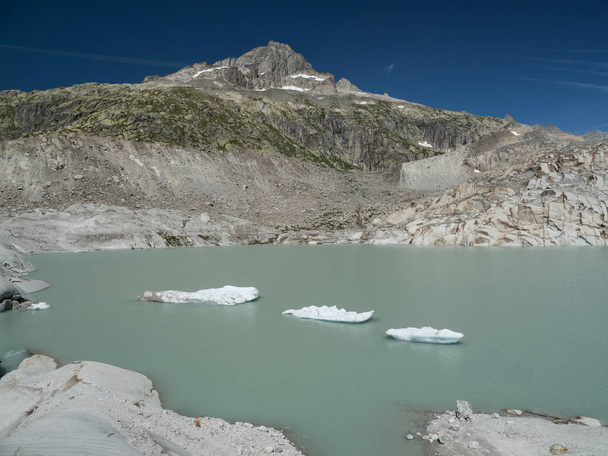 Alpine glacier lake with floating icebergs and sharp peaks - 写真・画像
