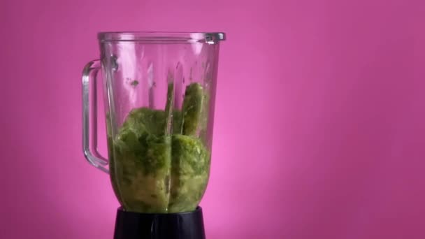 Sağlıklı yeşil smoothie Pembe arka planda bir blender ile harmanlanmış - Video, Çekim
