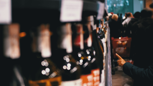 Kupující Vybrat alkoholické nápoje na regálech supermarketu v oddělení vína a vodky - Záběry, video