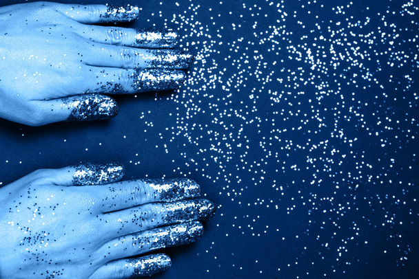 Two female hands with golden glitter on fingers on dark holiday background. - Zdjęcie, obraz
