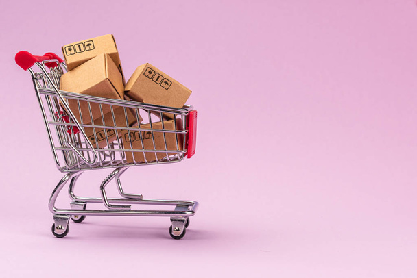 Cajas de papel en el carrito de la compra sobre fondo violeta con espacio de copia. Para el negocio de compras en línea, promoción y concepto de marketing
. - Foto, Imagen