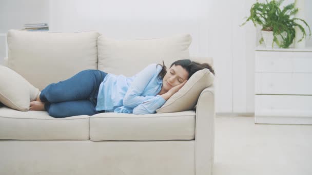 Langzaam. Tevreden brunette vrouwen slapen thuis op de bank. De vrouw droomt prettige dromen. 4k. - Video