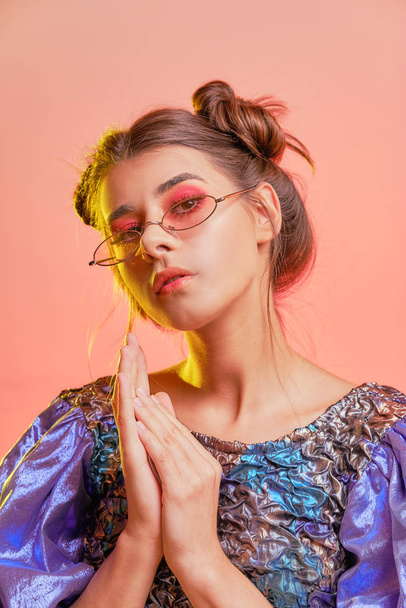 Portrait of an isolated young woman in glasses on a coral background. Close-up. - Photo, Image