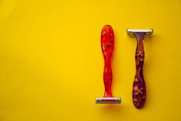 Nuevas maquinillas de afeitar desechables de color rosa para el afeitado seguro de la piel femenina con enfoque selectivo en el fondo amarillo con espacio de copia. Navaja de afeitar para un afeitado suave. Afeitadoras afiladas para la rutina higiénica personal
  - Foto, Imagen
