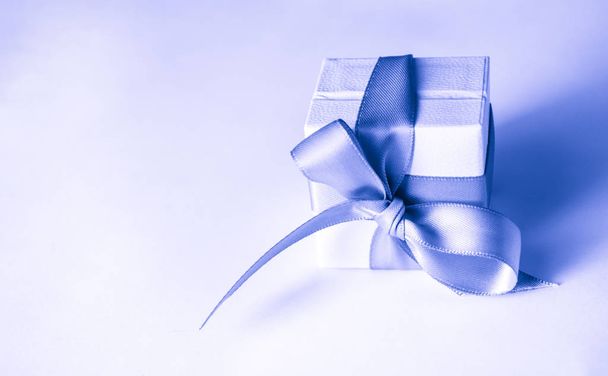 witte geschenkdozen met blauw lint op de klassieke blauwe pantalon achtergrond. Kerstmis of Valentijnsdag witte geschenkdoos  - Foto, afbeelding