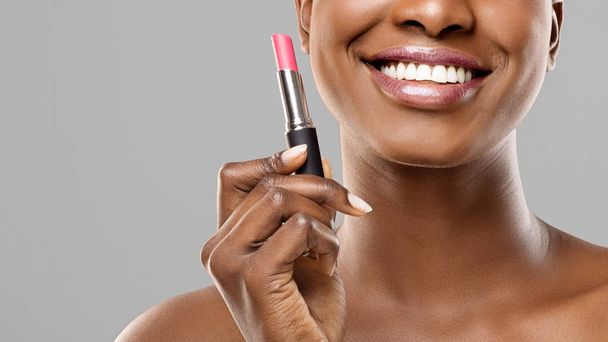 Beautiful afro girl holding pink lipstick in hand and smiling - Zdjęcie, obraz