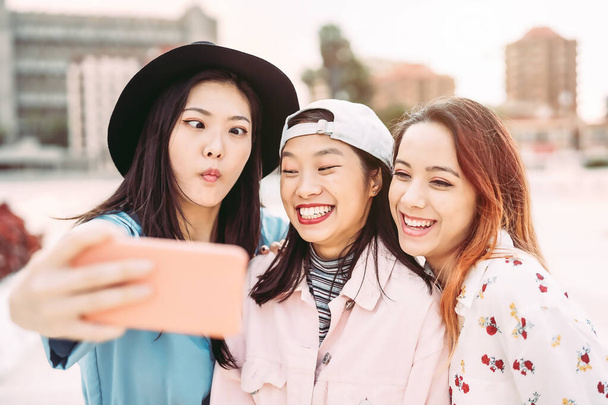 Mutlu Asyalı kızlar cep telefonlarıyla dışarıda selfie çekiyorlar - genç oyuncu sosyal arkadaşlar yeni moda teknolojileri kullanarak eğleniyorlar - insanlar, bin yıllık nesil ve gençlik yaşam tarzı konsepti - Fotoğraf, Görsel