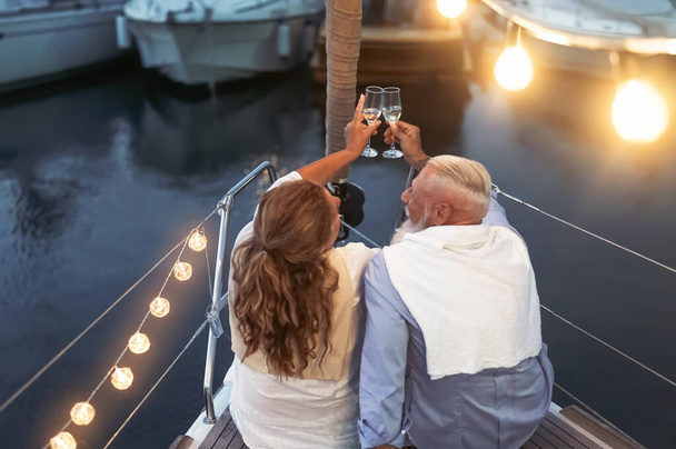 セーリングボートの休暇でシニアカップルトーストシャンパン-ボート旅行で結婚記念日を祝う楽しい成熟した人々 -愛の関係と旅行ライフスタイルのコンセプト - 写真・画像