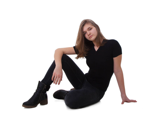 Portrait of a sitting girl in dark jeans and a dark T-shirt - Foto, Imagen