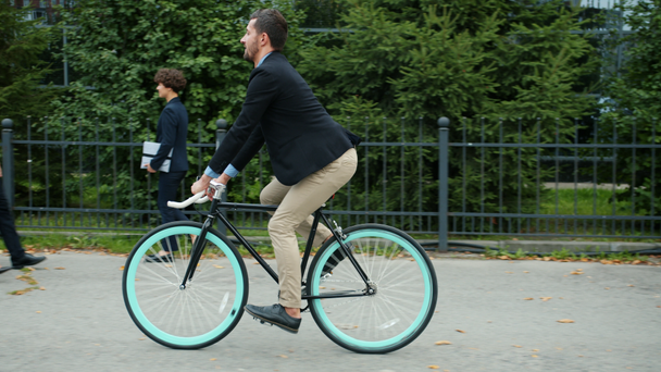 Handsome manager active person riding bike to office building in the morning - Záběry, video