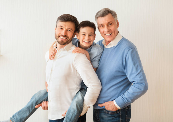 Homme avec fils et père aîné posant près du mur blanc
 - Photo, image