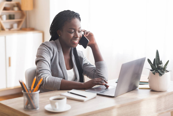 Businesswoman preto ocupado que trabalha no escritório com Smartphone e portátil
. - Foto, Imagem