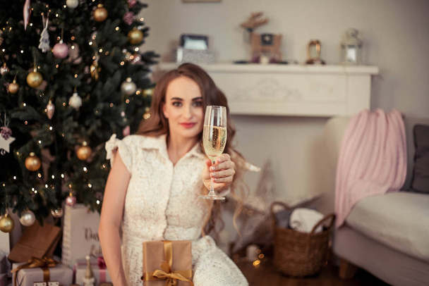 Una hermosa joven se sienta junto a un árbol de Navidad y abre regalos. Navidad. Año Nuevo. Acogedor
. - Foto, Imagen