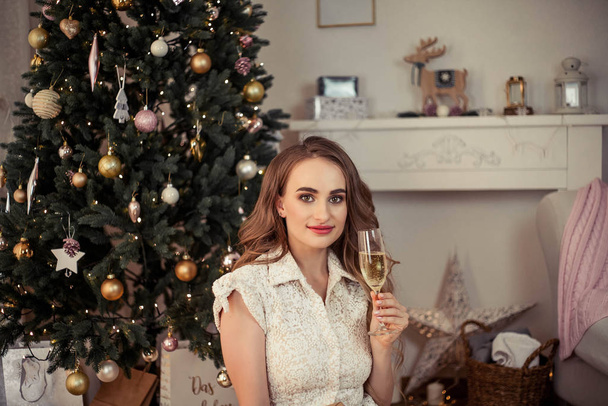 Egy gyönyörű fiatal nő ül egy karácsonyfa mellett, és ajándékokat nyit. Karácsonykor. Újév. Hangulatos. - Fotó, kép
