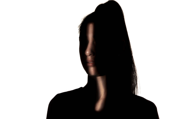 Dramatic portrait of a girl in the dark on white studio background. - Фото, изображение
