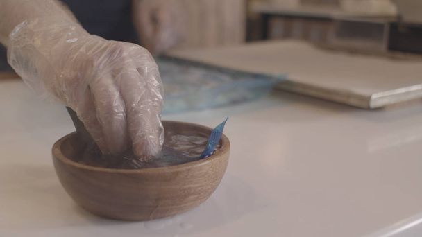 Close up of chef during preparation of the Japanese kitchen dish, food concept. Stock footage. Man in cooking gloves putting plastic bag with liquid substance into the bowl with hot water. - 写真・画像