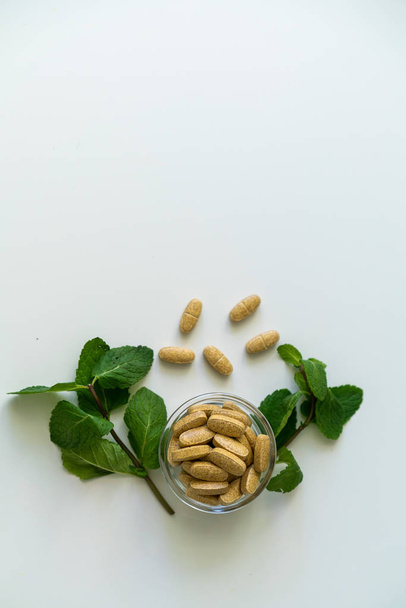 Nature health concept photo vertical orientation with pills and green herbs around, and copy space in upper part. - Foto, immagini