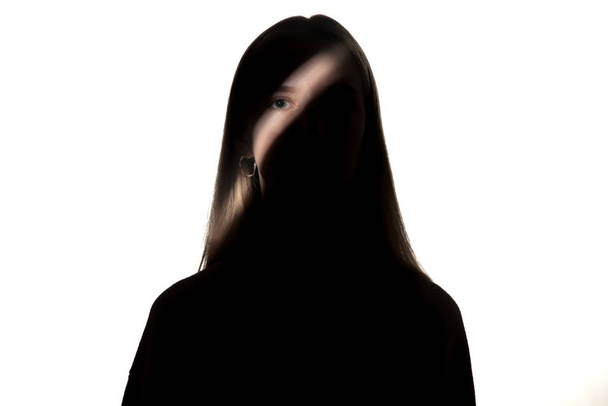 Dramatic portrait of a girl in the dark on white studio background. - Fotografie, Obrázek