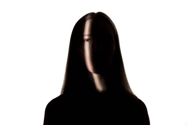 Dramatic portrait of a girl in the dark on white studio background. - Φωτογραφία, εικόνα