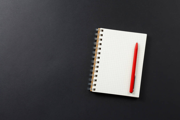ноутбук с красной ручкой на черном фоне - Фото, изображение