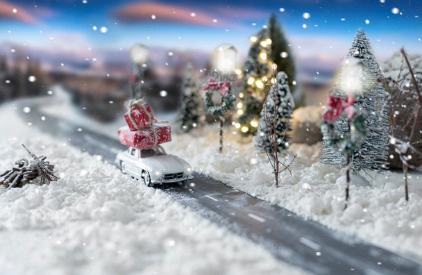 Miniatur-Oldtimer mit Weihnachtsgeschenken in verschneiter Winterlandschaft - Foto, Bild