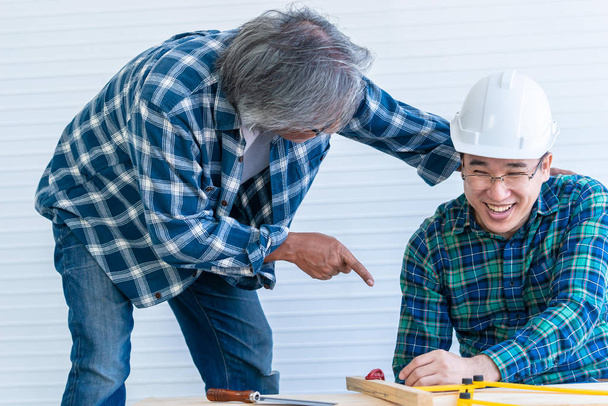 Starszy budowniczy chwali się i pomaga młodszemu pracownikowi w domu  - Zdjęcie, obraz