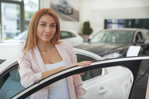 Gorgeous woman choosing a new car at the dealership - Foto, afbeelding