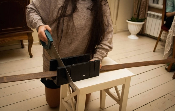The girl saws a wooden jamb - Foto, Imagen