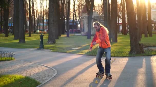 A professional roller rides great backwards on rollerblades between training cones, crossing legs. Active and sporting leisure in the central park of the city. Bottom-up shooting in slow motion. - Footage, Video