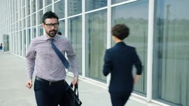 Slow motion of guy in formalwear running holding briefcase near office building - Video, Çekim