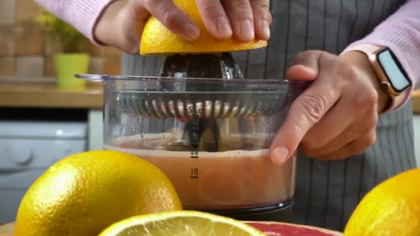 電気ジューサーで柑橘系ジュースを絞るキッチンの女性. - 映像、動画