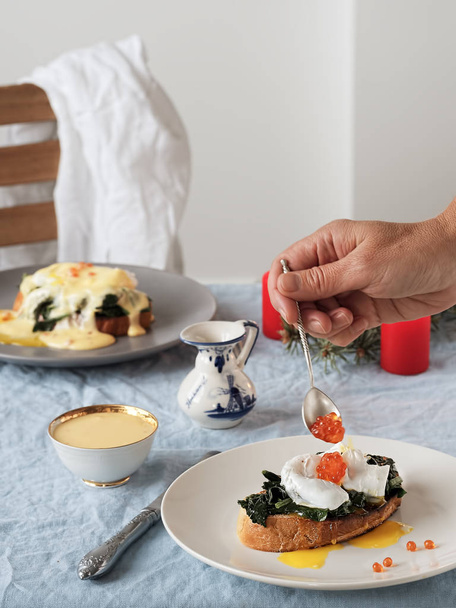 Eieren Benedict met Nederlandse ei en botersaus en rode kaviaar. Een close-up. Lekker ontbijt met gepocheerde eieren. Verticale oriëntatie. - Foto, afbeelding