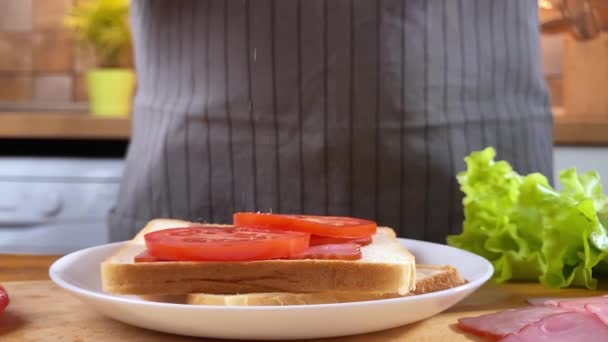 Ženské sendviče na kuchyni se salátem, slaninou a rajčaty - Záběry, video
