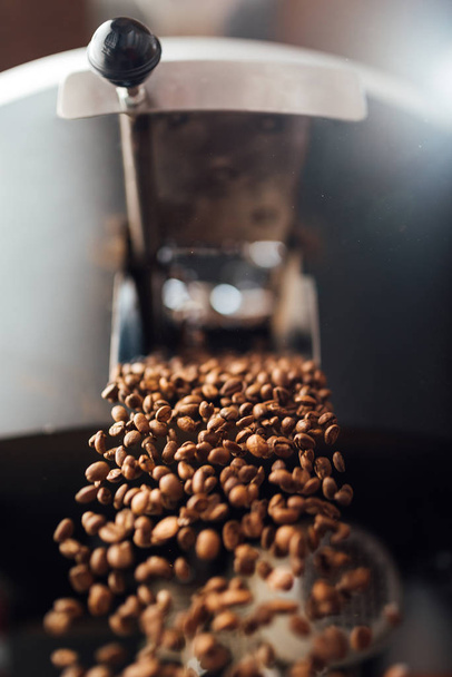 The flow of coffee beans from open flap of the cooling mixer of  - 写真・画像