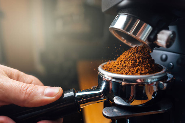 Gemahlener Kaffee, der mit einer Mühle in einen Portafilter gegossen wird - Foto, Bild